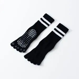 Black five-toe non-slip yoga socks with white stripes, mid-calf length for pilates gear.
