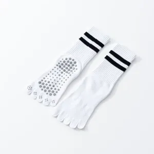 Detail view of white five-toe non-slip yoga socks featuring grip dots and sporty black stripes.