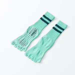Detailed view of mint green five-toe yoga socks with anti-slip silicone dots and stripes.