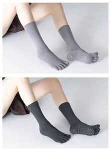Detail view of high tube five toe yoga socks with grip non slip dots in grey and dark grey.