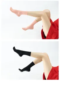 Detailed view of yoga grip socks with non-slip dots on sole in pink and black colors.