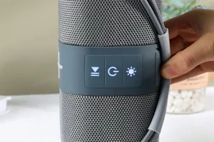Haut-parleur Bluetooth en tissu portable avec panneau de commande et une sangle pratique.