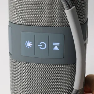 Vue détaillée d'enceinte bluetooth sans fil portable, tissu gris et boutons de commande LED.