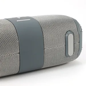 Vue détaillée d'un haut-parleur Bluetooth portable, design en tissu gris avec boutons en caoutchouc.