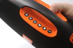 Close-up detail of portable Bluetooth speaker handle and control buttons, orange and black.