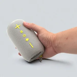 Portable wireless Bluetooth speaker with cylindrical mesh fabric design and bold buttons for outdoor use.