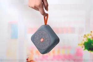 Altoparlante bluetooth portatile senza fili con cinturino arancione e griglia in tessuto.