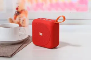Vista dettagliata dell'altoparlante Bluetooth portatile rosso wireless con cinturino sul tavolo bianco.