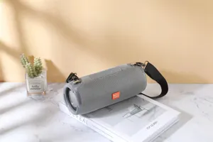 Detailed view of portable cylindrical fabric bluetooth speaker with strap and gray mesh finish.