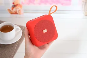 Vista di dettaglio dell'altoparlante bluetooth portatile con design arancione e cordino.