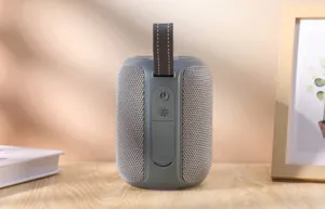 Détail d'enceinte Bluetooth portable cylindrique, avec sangle tissée et corps en tissu.