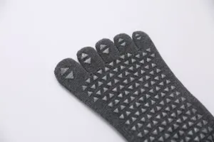 Close-up of grey five toe yoga socks with anti-slip silicone dots for stable pilates workout.
