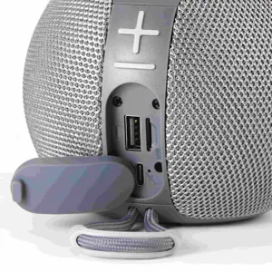 Detail view of portable wireless Bluetooth speaker charging port and rubber cover with strap.