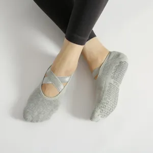Calcetines de yoga grises antideslizantes con tirantes cruzados para pilates y deporte.