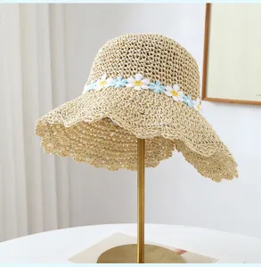 Vista dettagliata di un cappello di paglia intrecciato a mano con delicato ricamo di margherite.