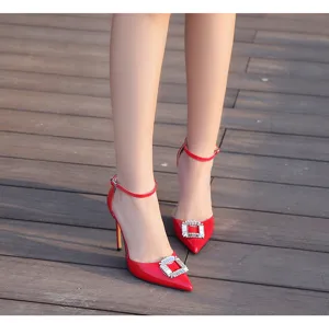 Zapatos de tacón de aguja de charol rojo con hebilla cuadrada de estrás y punta fina.