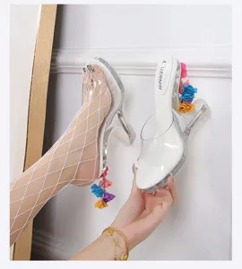 Gedetailleerd overzicht van doorzichtige hakken sandalen met bloemhangers en netkousen display.