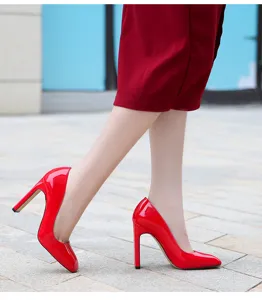 Detail view of red patent leather high heels, stylish thick heel women pumps for party.