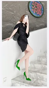 Detailed view of glossy green pointed high heels worn with a chic party outfit on stairs.