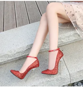 Detalle de tacones de aguja con purpurina roja, puntera puntiaguda y tacón metálico con correa.