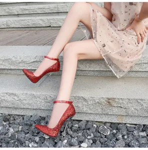 Primer plano detallado de zapatos de tacón rojo con purpurina y correa en escalones de piedra.
