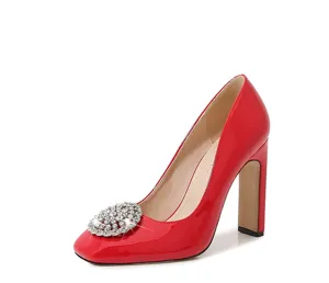 Detailed shot of red patent leather high heels with sparkling crystal square toe buckle.