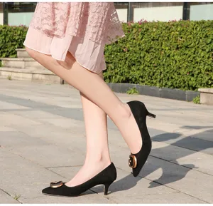 Vista detallada de zapatos negros de tacón bajo puntiagudos con hebilla metálica exterior.