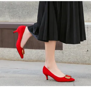 Vista detallada de zapatos de tacón rojo con punta fina y elegante hebilla metálica.