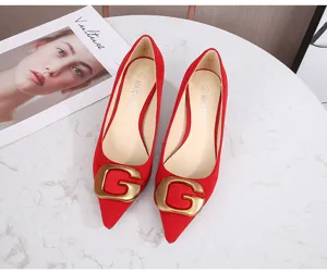Vista detallada de zapatos de tacón rojo con punta afilada y gran hebilla dorada G para mujeres.