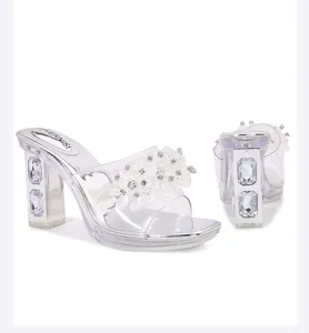 Clear crystal embellished chunky high heel mules with floral design and transparent straps.