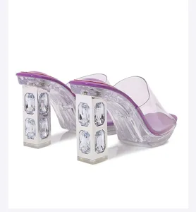 Close-up detail of chunky block high heels featuring sparkling crystals and clear straps.