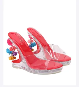 Rode hoge hakken met doorzichtige bandjes en kleurrijke bloemenhangers, modieuze sandalen.