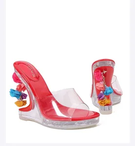 Transparante high heel sandalen met kleurrijke bloemenhangers en een rode glanzende binnenzool.