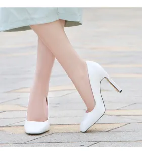 Detail view of elegant white patent leather high heels, stylish shallow mouth design for women.