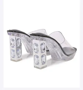 Detailed close-up of clear chunky high heel sandals with sparkling rhinestone crystal inserts.