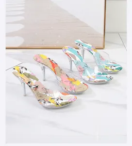 Elegantes mules de tacón alto transparente con plantilla estampada artística y tiras de PVC.