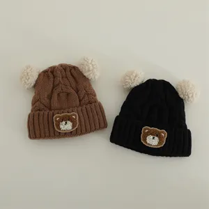 Cute baby knitted hat detail showing soft woolen fabric, warm double pom-pom and adorable bear patch.