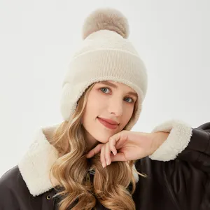 Vista detallada del gorro de invierno de punto cálido para mujer con pompón y orejeras.