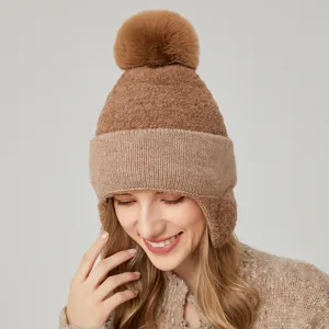Vista detallada de un elegante y acogedor gorro de invierno marrón con orejeras y pompón.