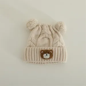 Cute baby knitted hat with double pom poms and cute bear patch, warm winter beanie for kids.
