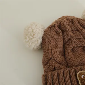 Close up of cute baby knitted hat detail, brown wool winter cap with fluffy pom poms.