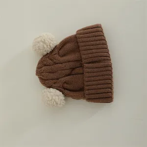 Infant cute brown knit hat with double white pom-poms for autumn and winter baby warmth.