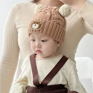 Baby knit beanie detail shot, cute bear patch and dual pom pom winter warm infant hat.
