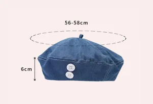 Gedetailleerde close-up van de blauwe denim baret met maataanduidingen en witte knopen.