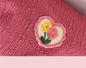 Close-up of pink seersucker beret detail, cute heart floral embroidery texture.