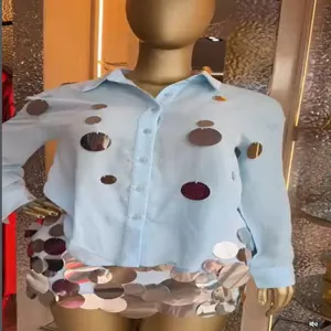 Detail view of a light blue long sleeve sequin shirt and skirt set on mannequin for vacation fashion.