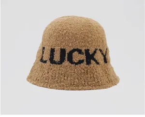 Vista detallada de un sombrero tipo pescador de felpa marrón de moda con letras negras.