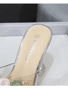Détail en gros plan de chaussures mules à hauts talons en strass et cristal transparent.