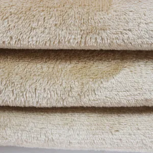 Close-up detail of soft beige plush fleece fabric, featuring a layered folded texture for apparel.