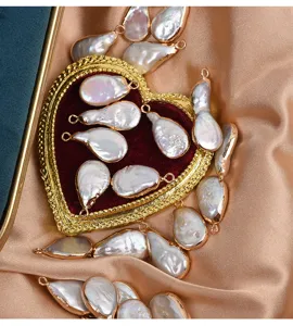 Primer plano detallado de colgantes de perlas barrocas en gota con bordes dorados para joyas.